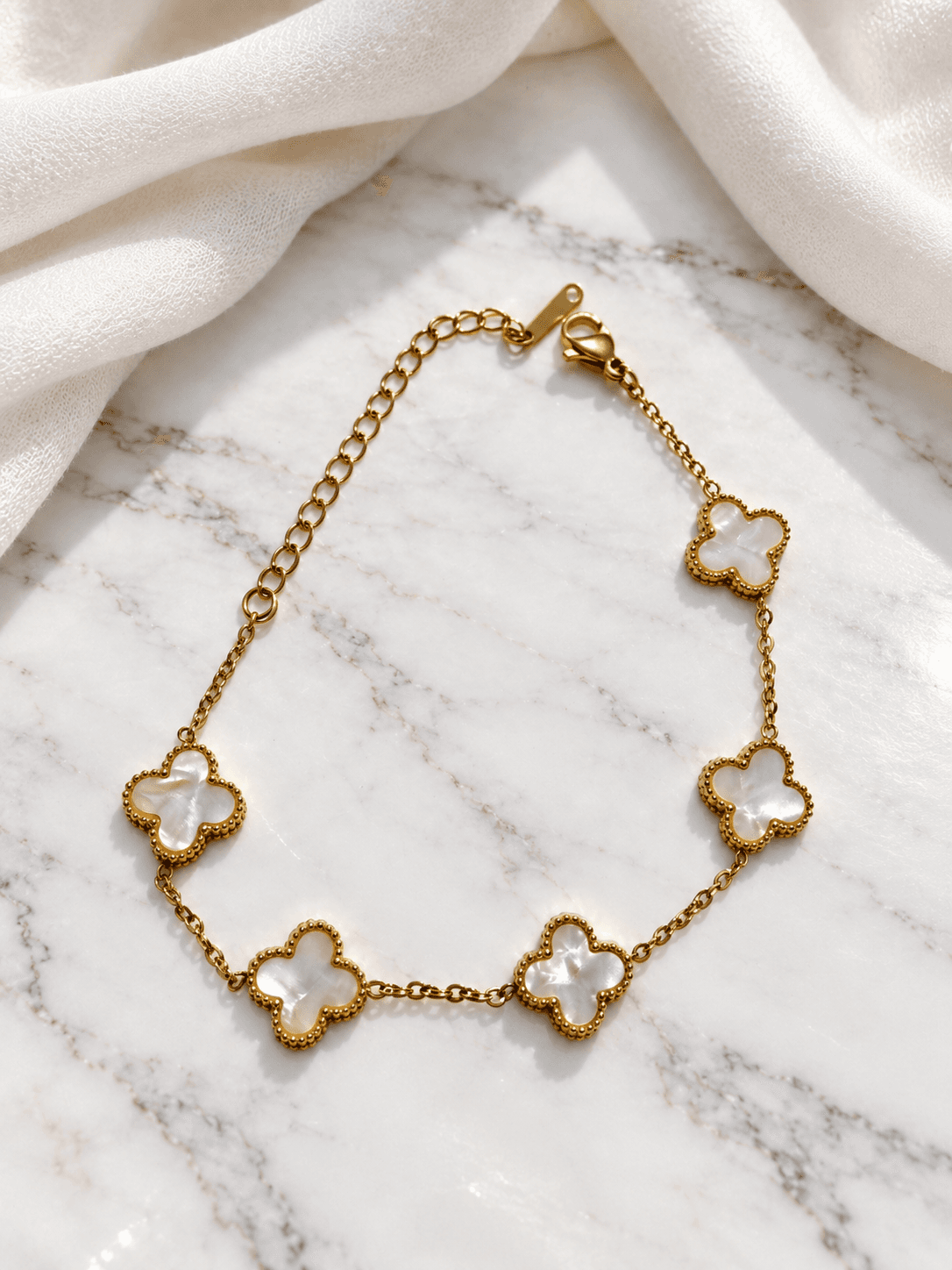 Mother of pearl clover bracelet on marble with ivory shawl