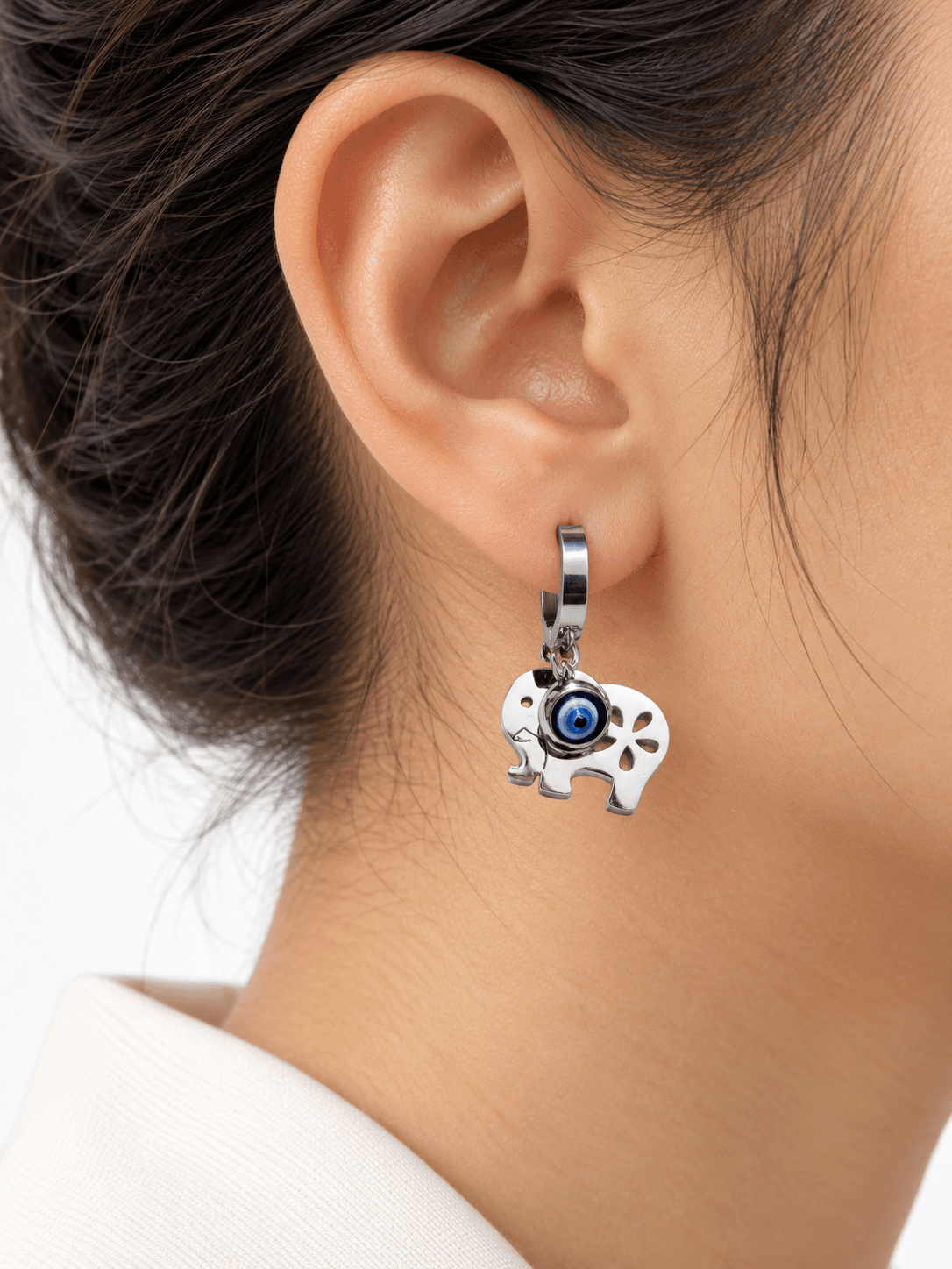 Silver elephant huggie earrings with blue evil eye charms on marble