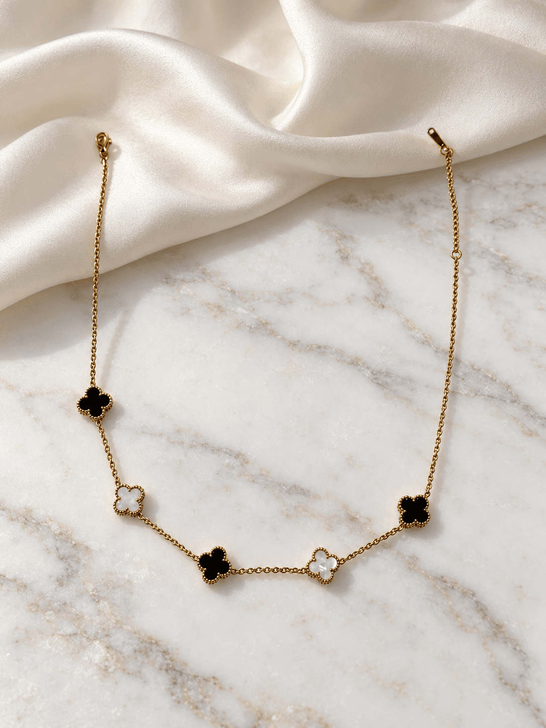 Black and white clover necklace on white marble