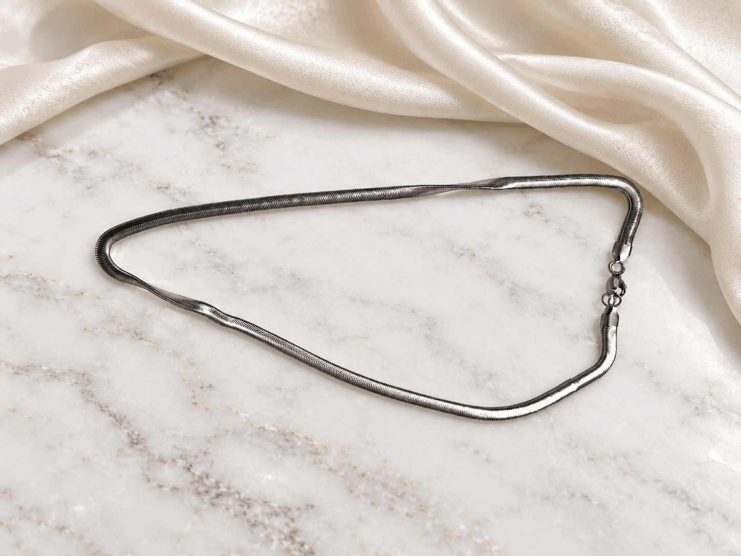 Silver herringbone chain necklace on marble